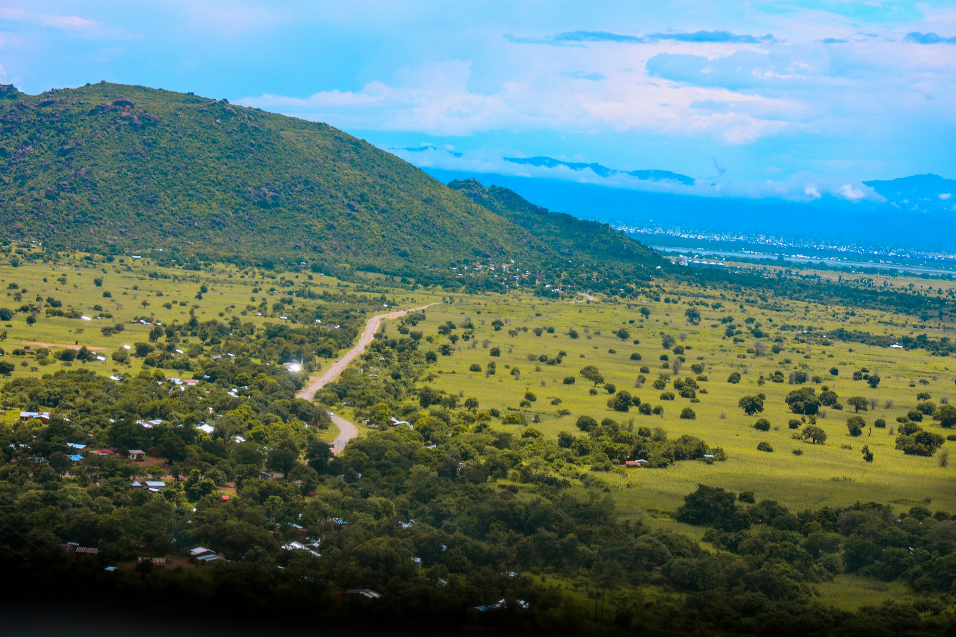 An expansive landscape of rolling green hills and scattered trees in northern Malawi