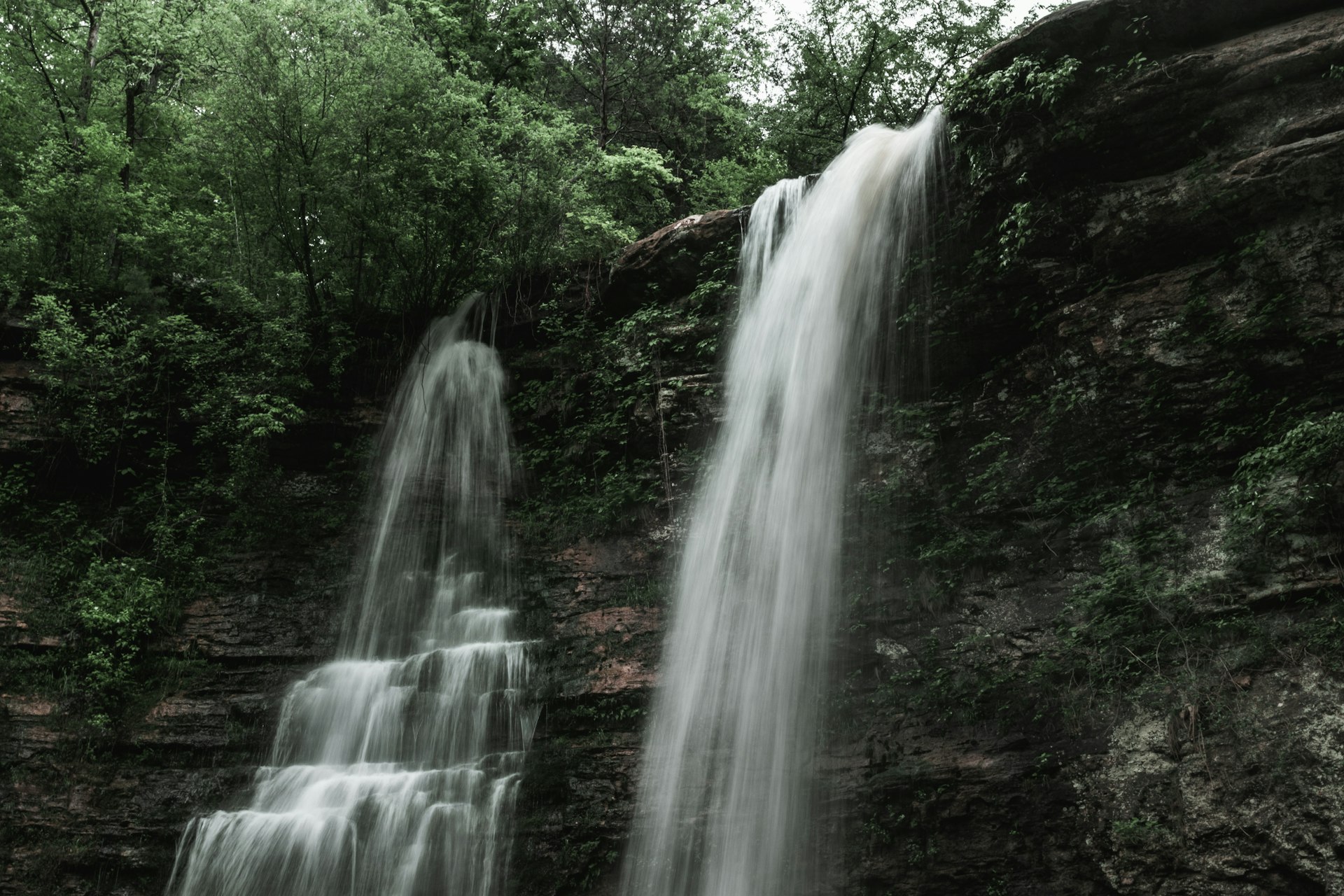 A tall waterfall plunging from a forested cliff