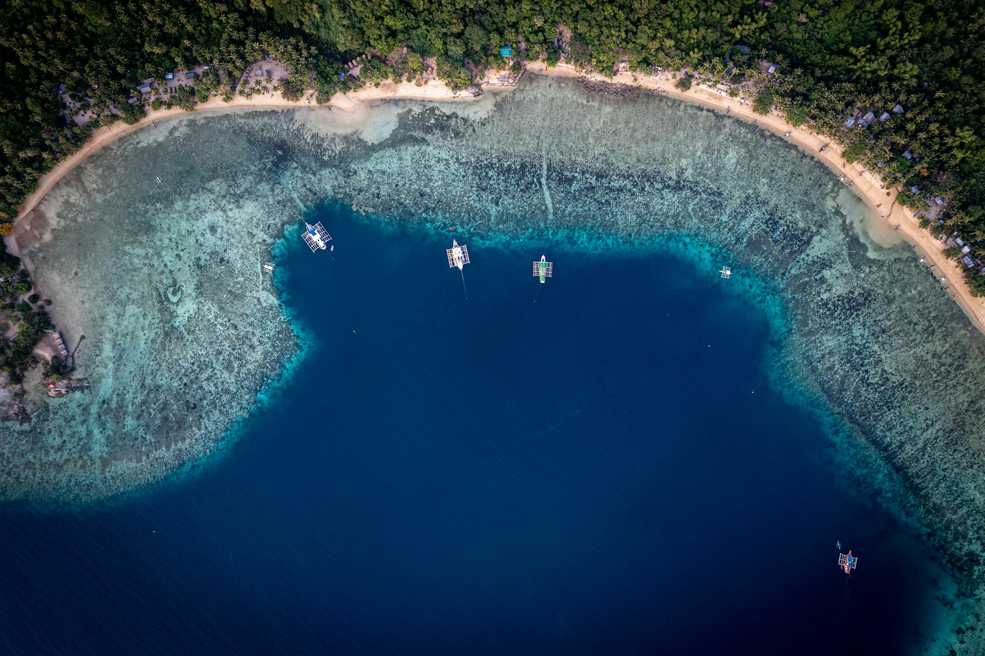 Boats anchored in a clear blue bay with coral reefs