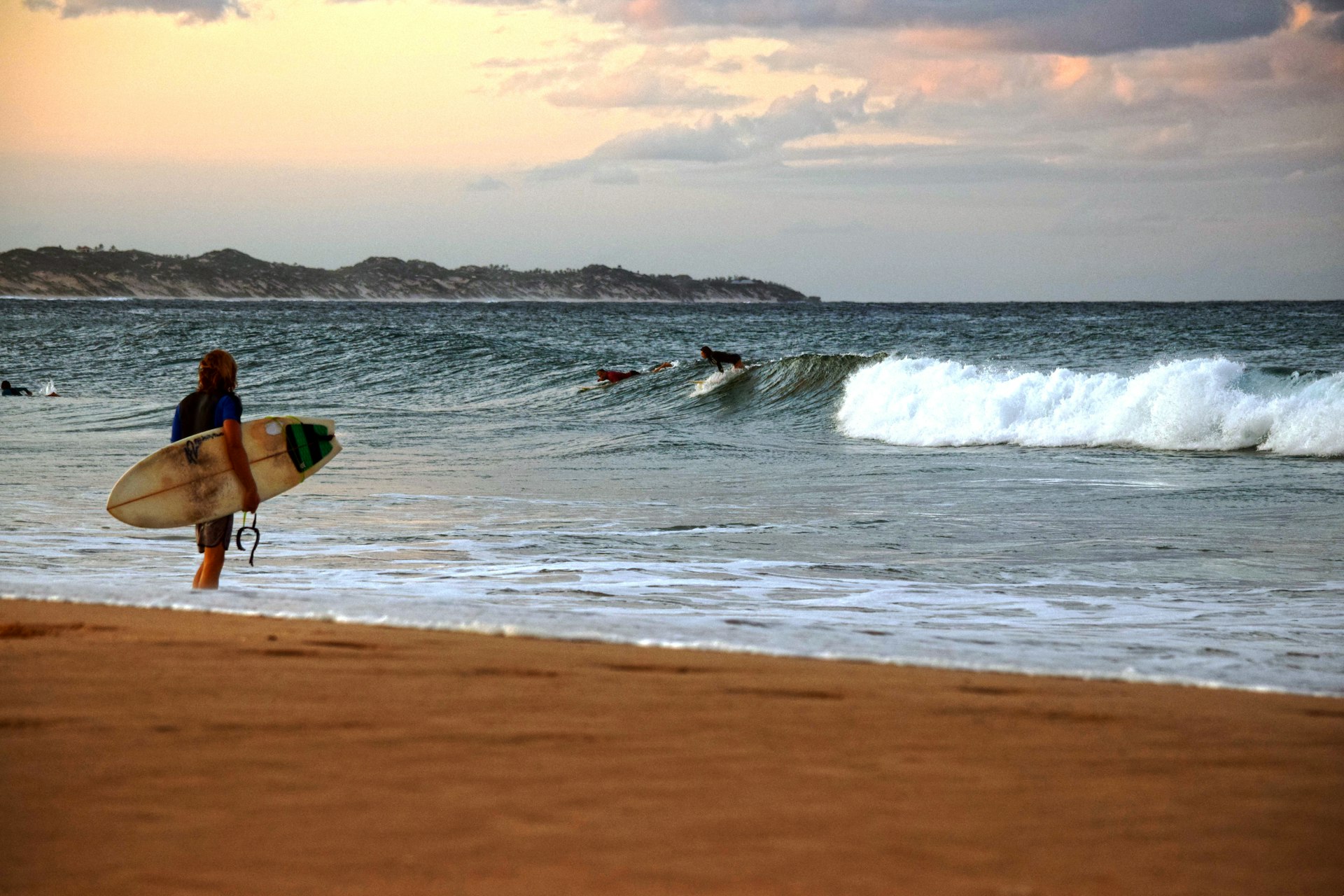 A surfer walking on Tofo Beach with the Indian Ocean behind