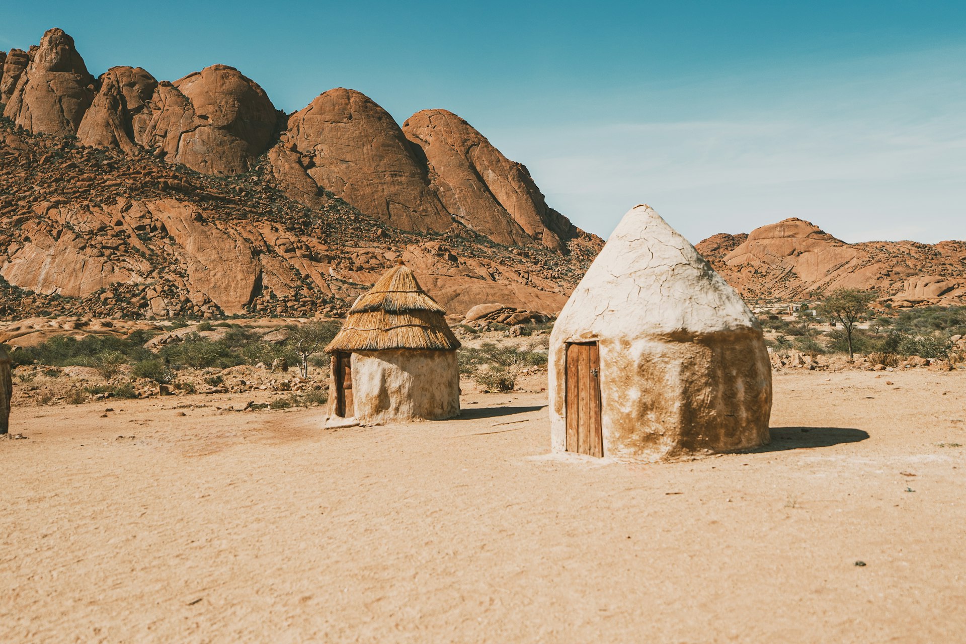 Traditional mud and thatch huts in a dry, rocky landscape
